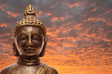 Buddha with orange clouds in the sunset