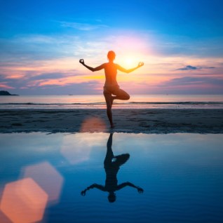 Silhouette of woman meditating on the sea beach. Yoga and fitness.